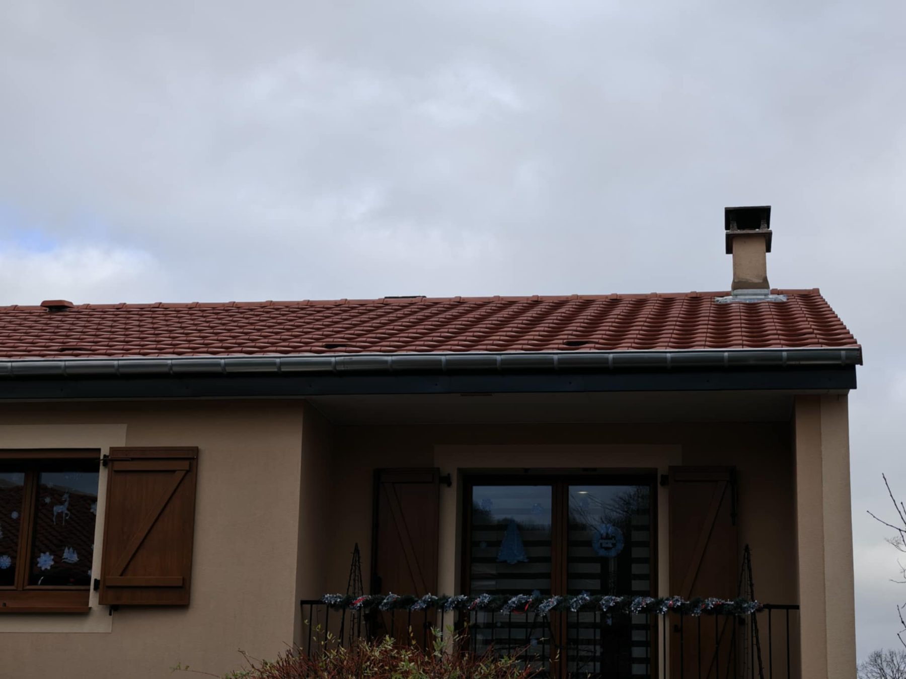 Gouttière neuve et abergement de cheminée sur un toit de tuiles rouges
