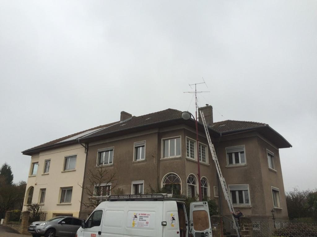 Camionnette J.B Toiture et échelle contre une grande maison