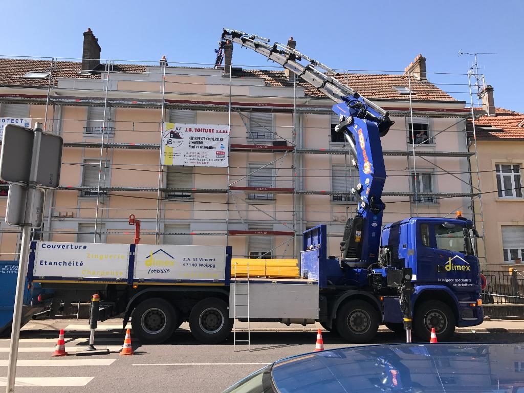Chantier J.B Toiture : échafaudage, bâche J.B Toiture et camion-grue devant un immeuble
